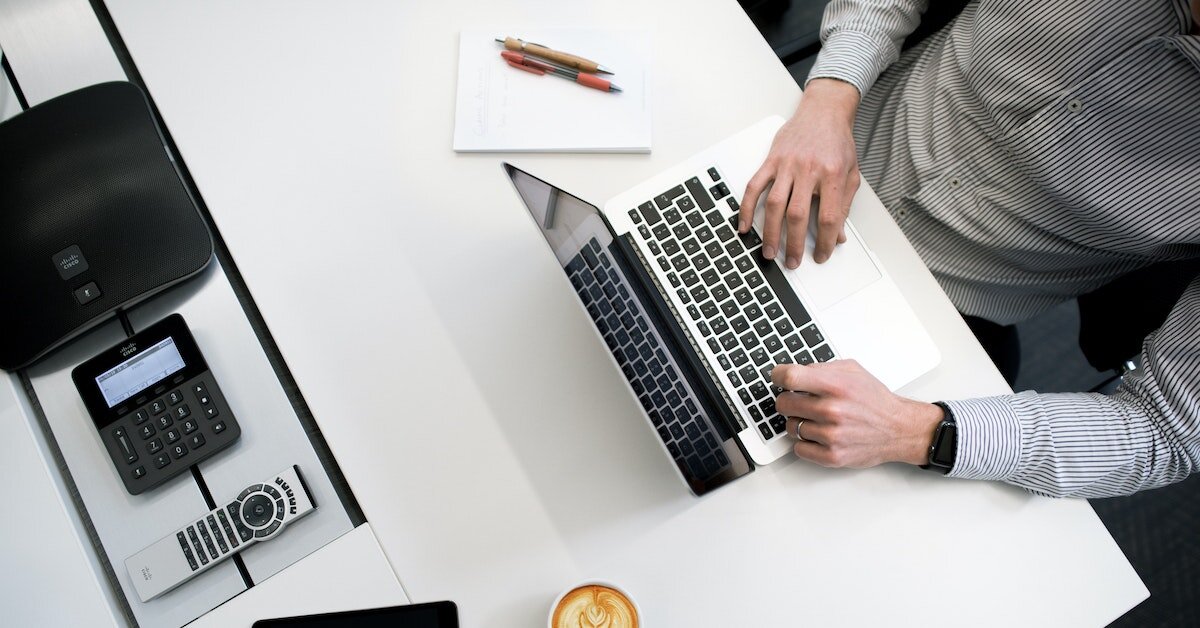 Overhead view of a broker working on a laptop at a desk Overhead view of a broker working on a laptop at a desk
